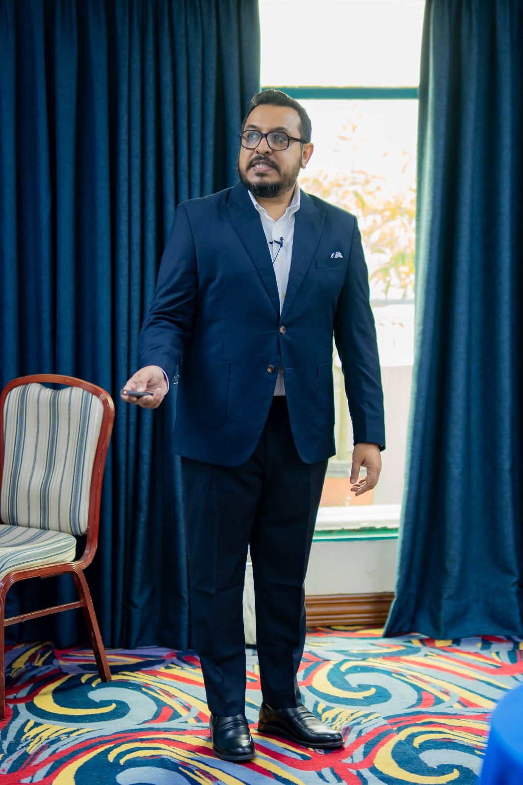 A speaker presenting in front of blue curtains